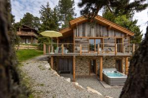 a log house with a hot tub and an umbrella at Ruggine - Forêt, luxe et montagne in Bolquere Pyrenees 2000