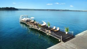Grand Hotel Portoroz 4* superior – Terme & Wellness LifeClass في بوروتوروج: رصيف به كراسي ومظلات على الماء