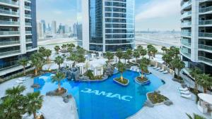 an aerial view of a resort pool with palm trees at Quill Residence at Paramount Towers 3 BR Creek View in Dubai