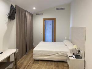 1 dormitorio con 1 cama blanca y TV en Eurocity Hotel Santander Centro, en Santander