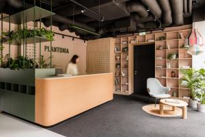 a woman standing behind a counter in a room with plants at PLANTONIA Aparthotel in Kraków