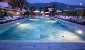 ein Swimmingpool mit Stühlen und Sonnenschirmen in der Nacht in der Unterkunft Palace Hotel Città in Arco