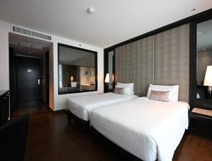 a large bedroom with two beds and large windows at Mövenpick Hotel Sukhumvit 15 Bangkok in Bangkok