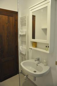 Baño blanco con lavabo y espejo en B&B Casa Soresina, en Offagna