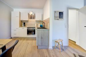 a kitchen with white cabinets and a wooden floor at Rehdamm in Heide