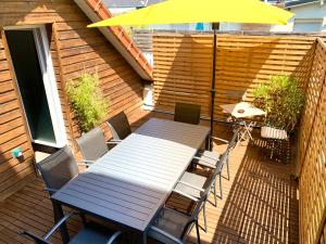 une table et des chaises sur une terrasse avec un parasol dans l'établissement Eco-Appart'hôtel Rouen / SLT, à Rouen