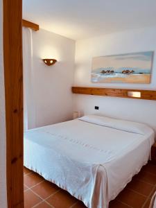 ein Schlafzimmer mit einem weißen Bett und einem Gemälde an der Wand in der Unterkunft Hotel Pop in Cala Gonone