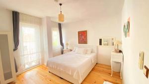 1 dormitorio blanco con 1 cama blanca y 2 ventanas en Pervin Hanım Konağı, en Alacati