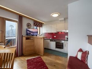 une cuisine avec des placards blancs et un mur rouge dans l'établissement Berghaus Koglmoos, à Auffach