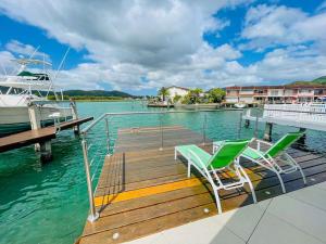 a dock with two chairs and a boat on the water at Villa 238A Jolly Harbour in Jolly Harbour