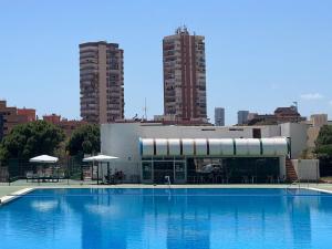 a swimming pool in front of a building with two tall buildings at Панорамная квартира с 1 спальней в Бенидорме in Benidorm