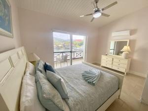 a bedroom with a bed with a ceiling fan and a window at Villa 218G Jolly Harbour in Jolly Harbour
