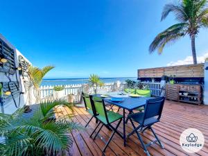 - une table et des chaises sur une terrasse avec vue sur la plage dans l'établissement Les Mosalas - 2 et 3 étoiles - pieds dans l'eau - Lagon de Saint-Leu, à Saint-Leu