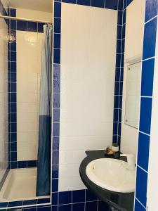 baño azul y blanco con lavabo y bañera en Karina Apartments en Supetar