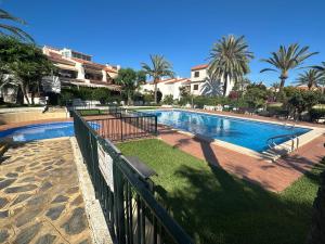 a swimming pool in a resort with palm trees at Bungalow Santa Pola del Este in Gran Alacant