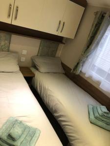 Duas camas num pequeno quarto com uma janela em Seaview Retreat unavailabl3 em Mainsriddle
