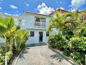 a white house with palm trees in front of it at Villa 218E Jolly Harbour in Jolly Harbour