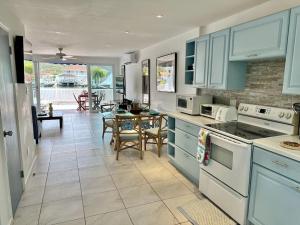Villa 218E Jolly Harbour في جولي هاربور: مطبخ مع دواليب زرقاء وطاولة مع كراسي
