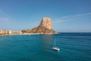 a boat in the water in front of an island at Apartamentos Vista Bella in Calpe