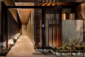 a hallway leading to a building with plants at Oyado Kawaramachi Gojo（御宿 河原町五条） in Kyoto