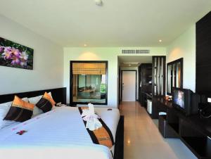 um quarto com uma grande cama branca e uma televisão de ecrã plano em H.R.K.Resort em Patong Beach