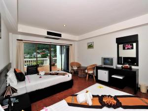 1 dormitorio con 2 camas, escritorio y TV en H.R.K.Resort en Patong Beach