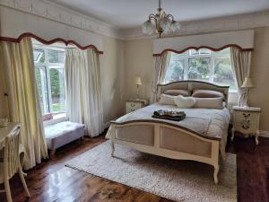 a bedroom with a large bed and two windows at Rooms at Ballysax House in The Curragh