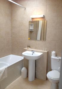 a bathroom with a sink and a tub and a toilet at The Riviera Hotel & Apartments - Alum Chine in Bournemouth