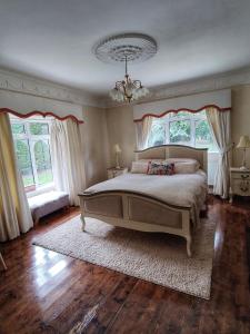 um quarto com uma cama grande e 2 janelas em Rooms at Ballysax House em The Curragh