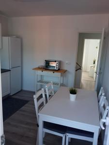 uma cozinha com uma mesa e uma mesa e cadeiras brancas em APARTAMENTOS LA CAPILLA em Vilanova de Arousa