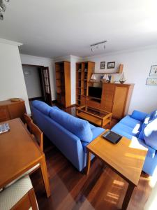 een woonkamer met een blauwe bank en een tafel bij Nuevo! 3 habitaciones con garaje privado in Santander