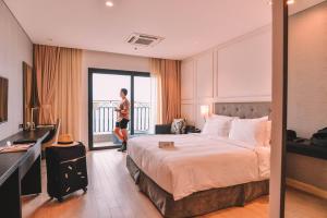 Danang Bay View Apartment - Phòng Code chủ في دا نانغ: امرأة تقف في غرفة فندق بسرير