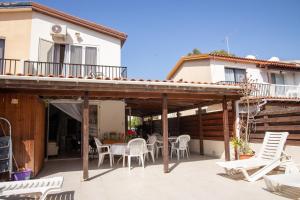 a patio with white chairs and tables and a building at Spyros No23 Charming Oceanview Maisonette in Meneou