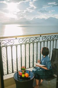a woman sitting on a balcony with a bowl of fruit at Danang Bay View Apartment - Phòng Code chủ in Danang