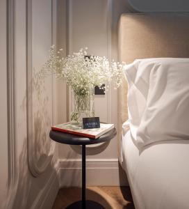 a table with a book and flowers on it next to a bed at Oliveira Rooms in Valencia