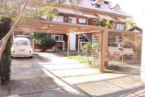 a car parked under a wooden pergola in front of a house at Casa Ourinhos Pet Friendly in Ourinhos