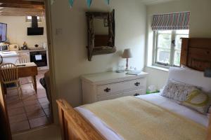 a bedroom with a bed with a mirror and a kitchen at Dairy Cottage Luxury B&B in Attleborough
