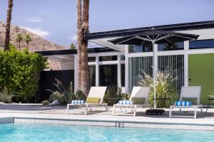 a group of chairs and an umbrella next to a swimming pool at The Three Fifty Hotel, A Kirkwood Collection Hotel in Palm Springs