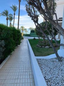 un camino de ladrillo con árboles y palmeras en Apartamento Alicante San Juan playa 1ª línea, en Benimagrell