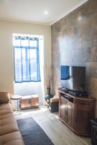 a living room with a couch and a flat screen tv at Casa da Memória in Angra do Heroísmo