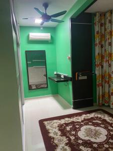um quarto verde com uma ventoinha de tecto e um espelho em NO 5 NAZIRIN HOMESTAY Tmn Desa Manjung em Lumut
