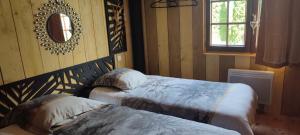 1 dormitorio con 2 camas y espejo en la pared en Domaine le lanis "cabane de Pauline", en Saint-Girons