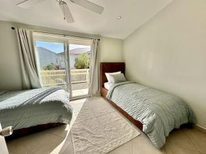 1 dormitorio con 2 camas y ventana grande en Sunshine Villa en Jolly Harbour
