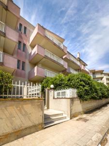 a pink apartment building with stairs and a fence at Casa Vacanza Germano - Vivi un soggiorno da sogno - 160m2 di comfort e vista mare in Sicilia! in Pachino