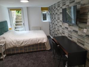 Schlafzimmer mit einem Bett, einem Schreibtisch und einem TV in der Unterkunft Lyndene House in Huddersfield