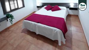 a bedroom with a large white bed with red pillows at Hostal Rte. Casa Miguel in Matalascañas