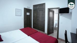 a bedroom with a bed and two wooden doors at Hostal Rte. Casa Miguel in Matalascañas