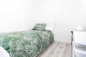 a bedroom with a bed with a green and white comforter at Apartamento Roncudo 4º planta in A Coruña