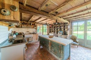 にあるLa Clayette - Charmante maison avec piscine privéeの木製の天井と大きな島のある広いキッチンが備わります。