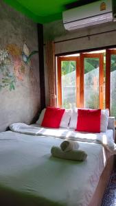 a bedroom with a bed with red pillows and avertisement at Pai Family Resort in Pai